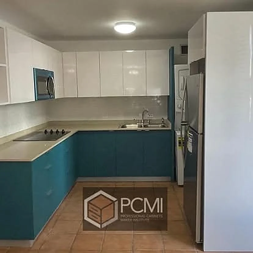Cocina en U con gabinetes altos blancos y bajos en turquesa, piso de losa terracota.