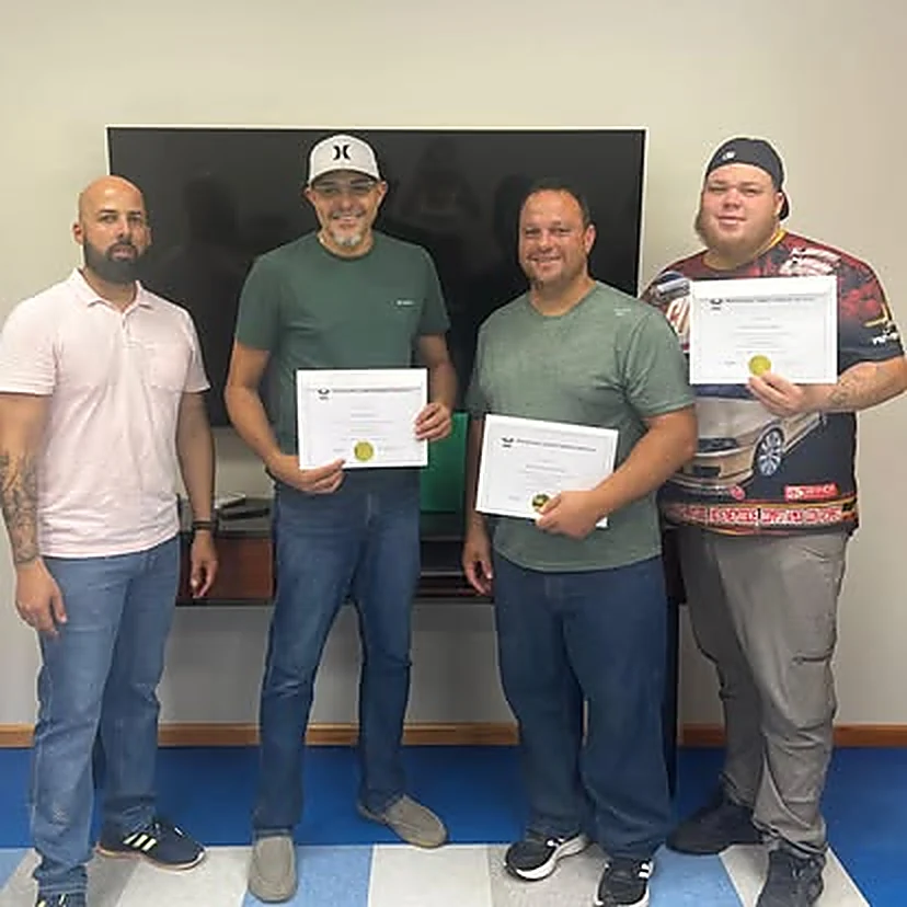 Cuatro estudiantes con sus certificados junto al instructor al finalizar el taller.