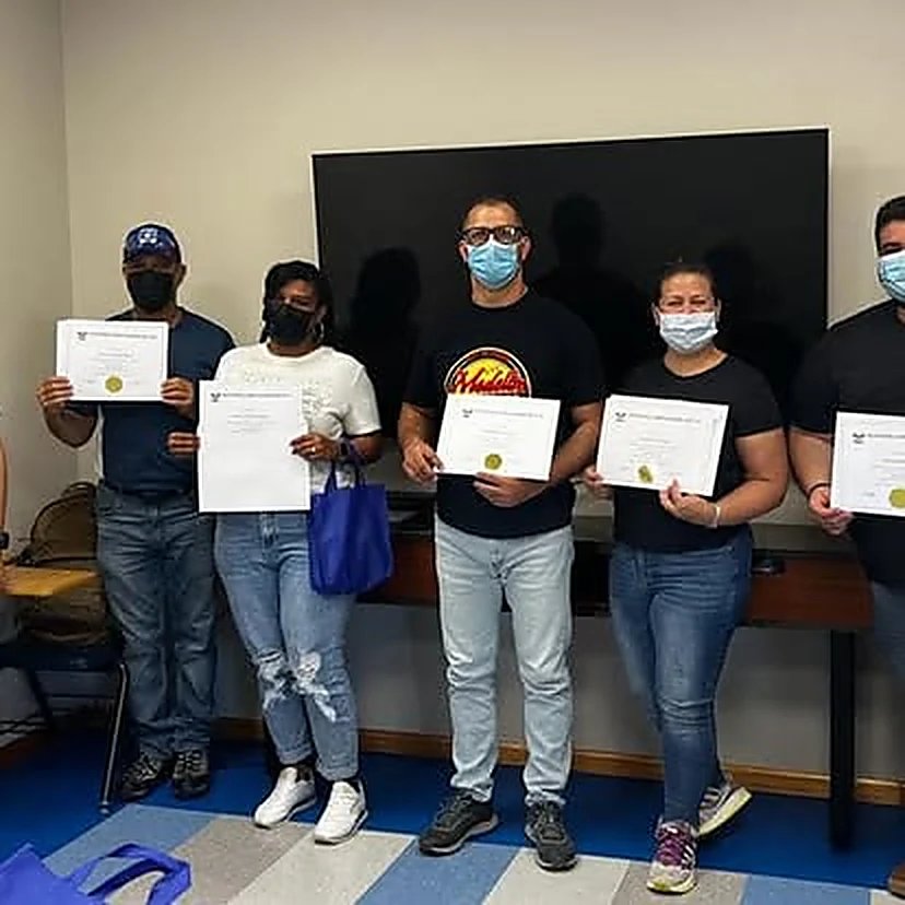 Grupo mixto de estudiantes, hombres y mujeres, sosteniendo sus certificados al terminar el curso.